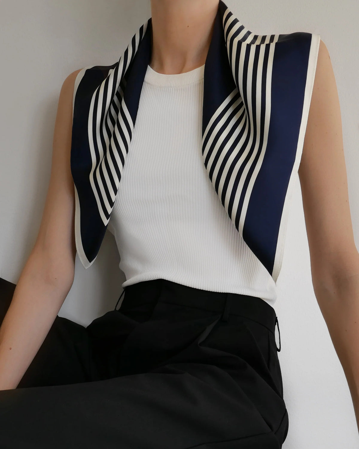 Striped Scarf in Navy by Lescarf draped over the shoulders with a white ribbed top and black trousers