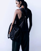 Model seen from behind carrying the ALEO Romy Woven Tote in Black on her arm