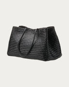 ALEO Romy Woven Tote in Black, three-quarter view showing the woven side, on soft stone background