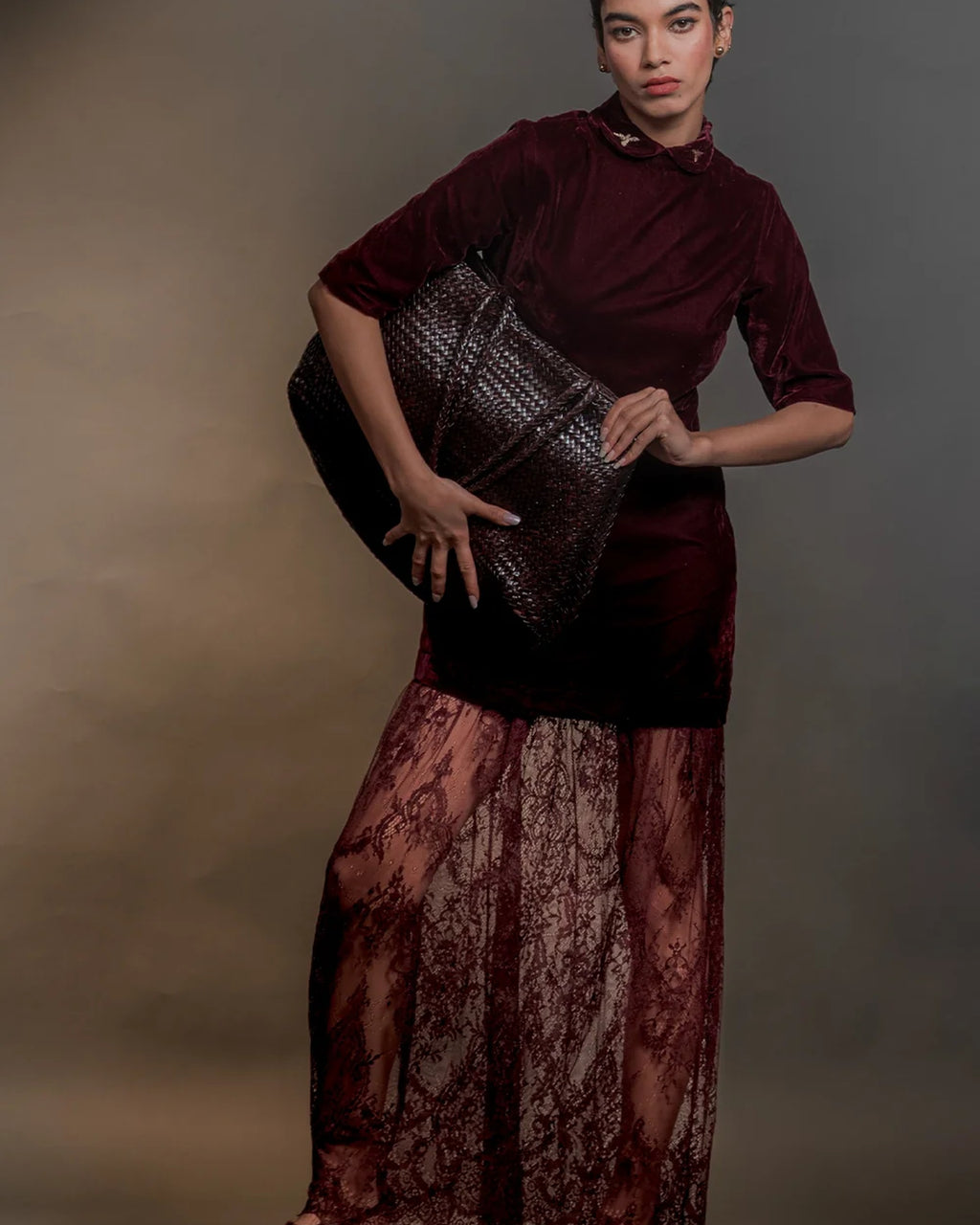 Model holding the ALEO Romy Woven Tote in Crema under her arm, styled with a velvet top and lace skirt
