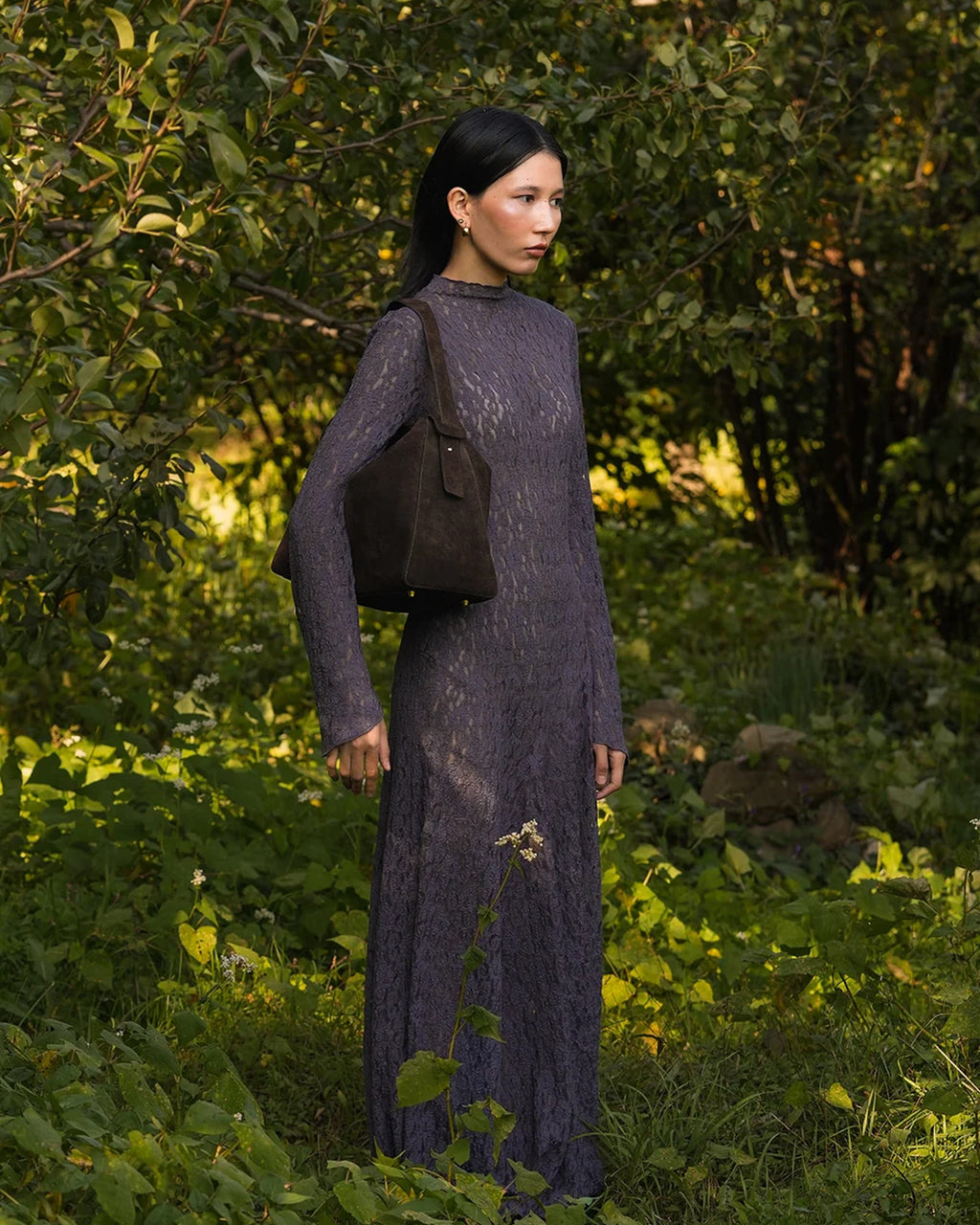 Model wearing the ALEO Shiloh Suede Shoulder Bag in Crema on her shoulder in a garden