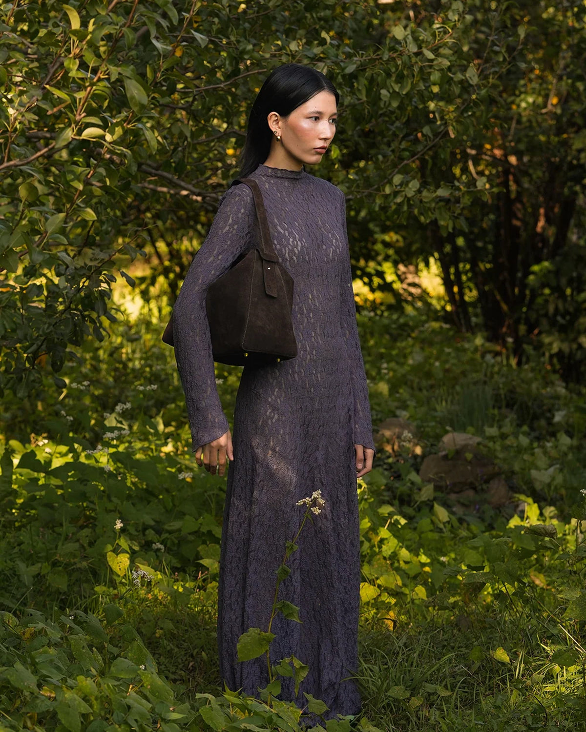 Model wearing the ALEO Shiloh Suede Shoulder Bag in Crema on her shoulder in a garden