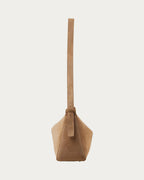 ALEO Shiloh Suede Shoulder Bag in Toffee, side view with the long cross-body strap, on soft stone background