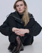 Model seated wearing Augusta chocolate metallic leather ankle boots
