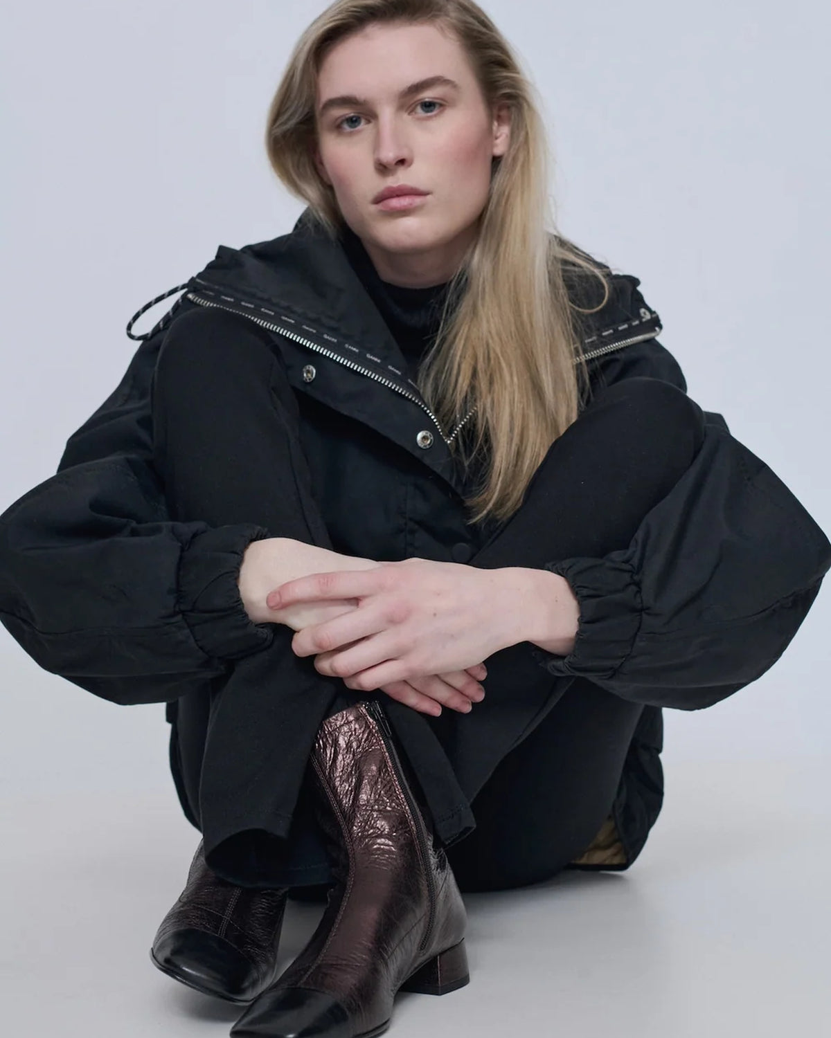 Model seated wearing Augusta chocolate metallic leather ankle boots