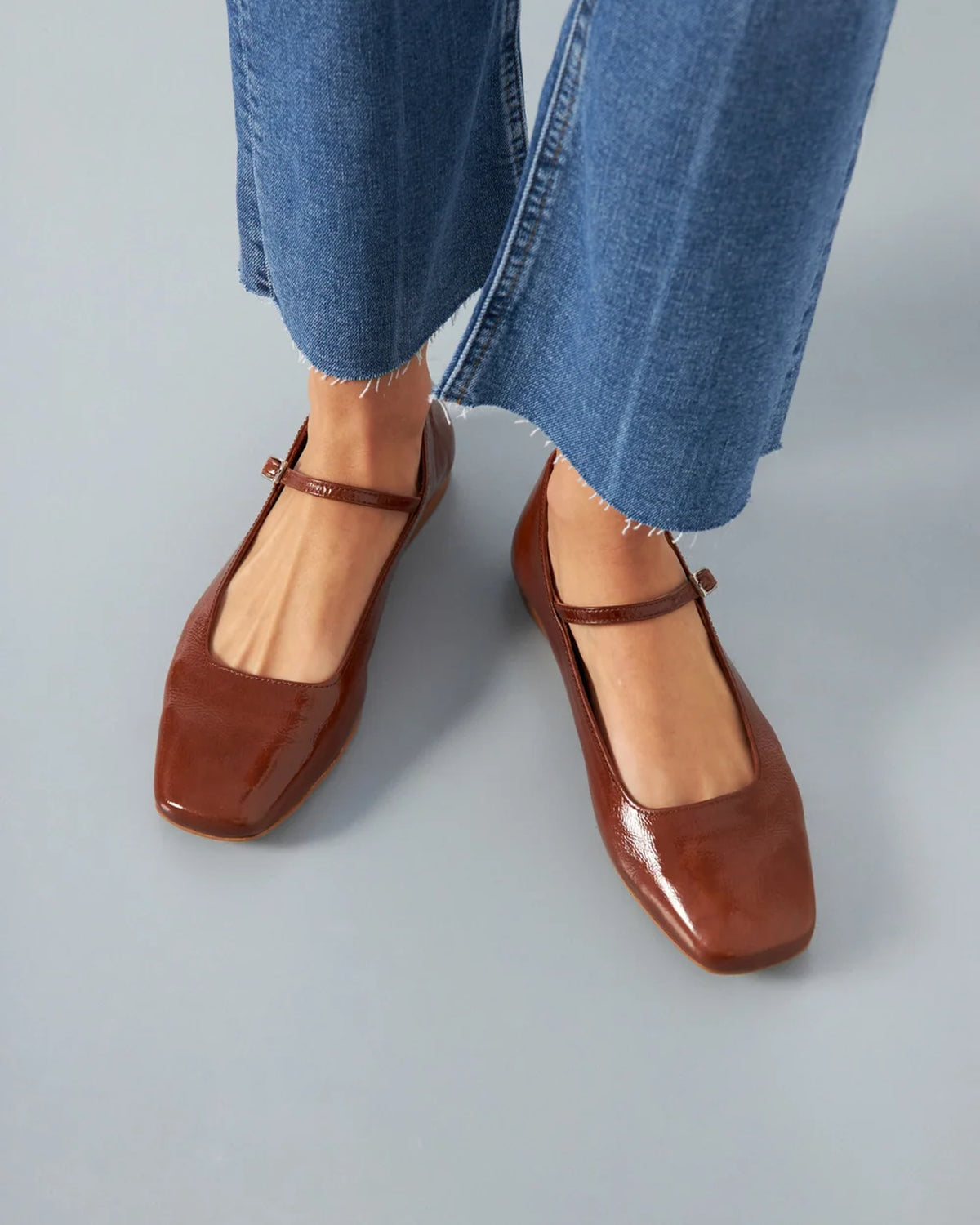 Close-up of model wearing Augusta saddle patent leather Mary Jane flats with cropped jeans