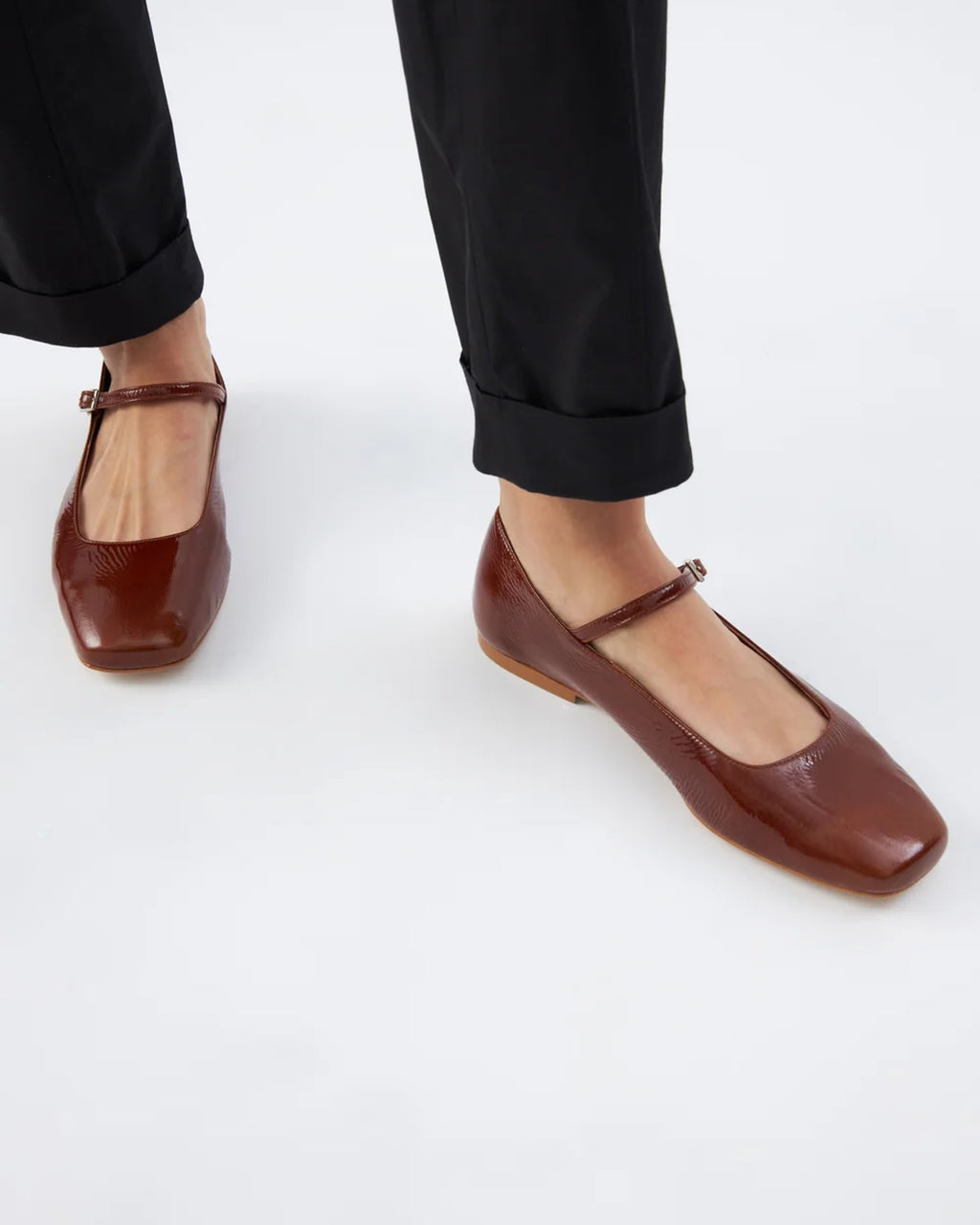 Augusta saddle patent leather Mary Jane flats worn with black cuffed trousers