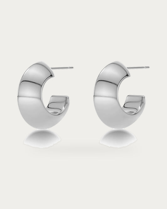 Edblad Bead Large Creole Earrings In Steel, a pair of chunky polished steel creole hoop earrings with asymmetrical triangle shapes, product photo on a soft off-white background