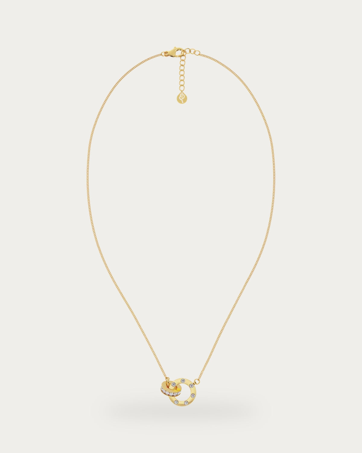 Edblad Ida Mini Necklace In Gold, a fine gold chain necklace with an extender chain and a pendant of two interlocked rings set with clear stones, product photo on a soft off-white background
