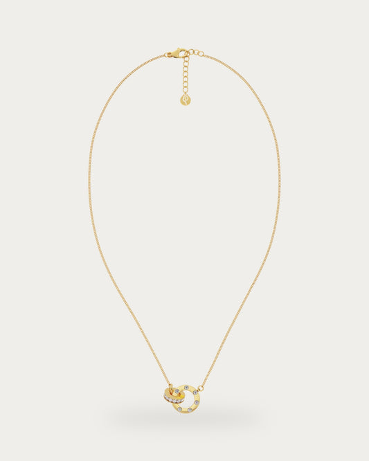 Edblad Ida Mini Necklace In Gold, a fine gold chain necklace with an extender chain and a pendant of two interlocked rings set with clear stones, product photo on a soft off-white background