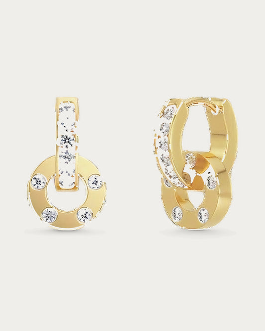 Edblad Ida Orbit Earring In Gold, a pair of gold earrings set with clear stones, one with a hanging ring, product photo on a soft off-white background