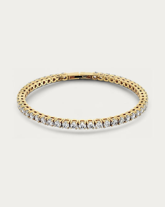 Edblad Tennis Bracelet In Gold, a gold bracelet set with small clear stones all the way around, product photo on a soft off-white background