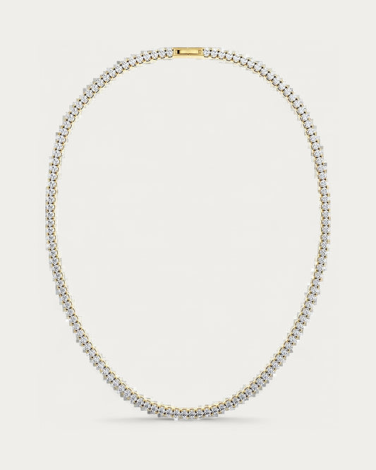 Edblad Tennis Necklace In Gold, a gold necklace set with small clear stones all the way around, product photo on a soft off-white background
