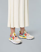 Model wearing Flower Mountain Yamano 3 Multi sneakers with a pleated skirt