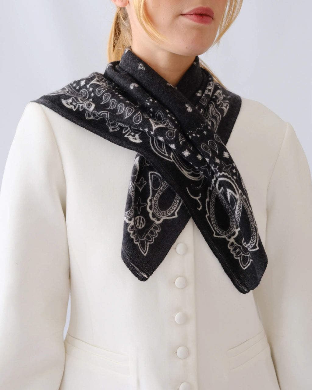 Lescarf cashmere paisley scarf in black with cream print, worn crossed at the neck with a white jacket
