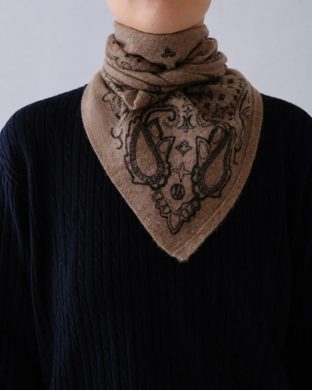 Lescarf cashmere paisley scarf in greige worn folded at the neck over a navy knit