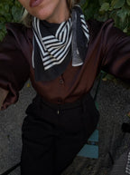 Lescarf cashmere striped scarf in black and cream, worn at the neck with a brown satin shirt