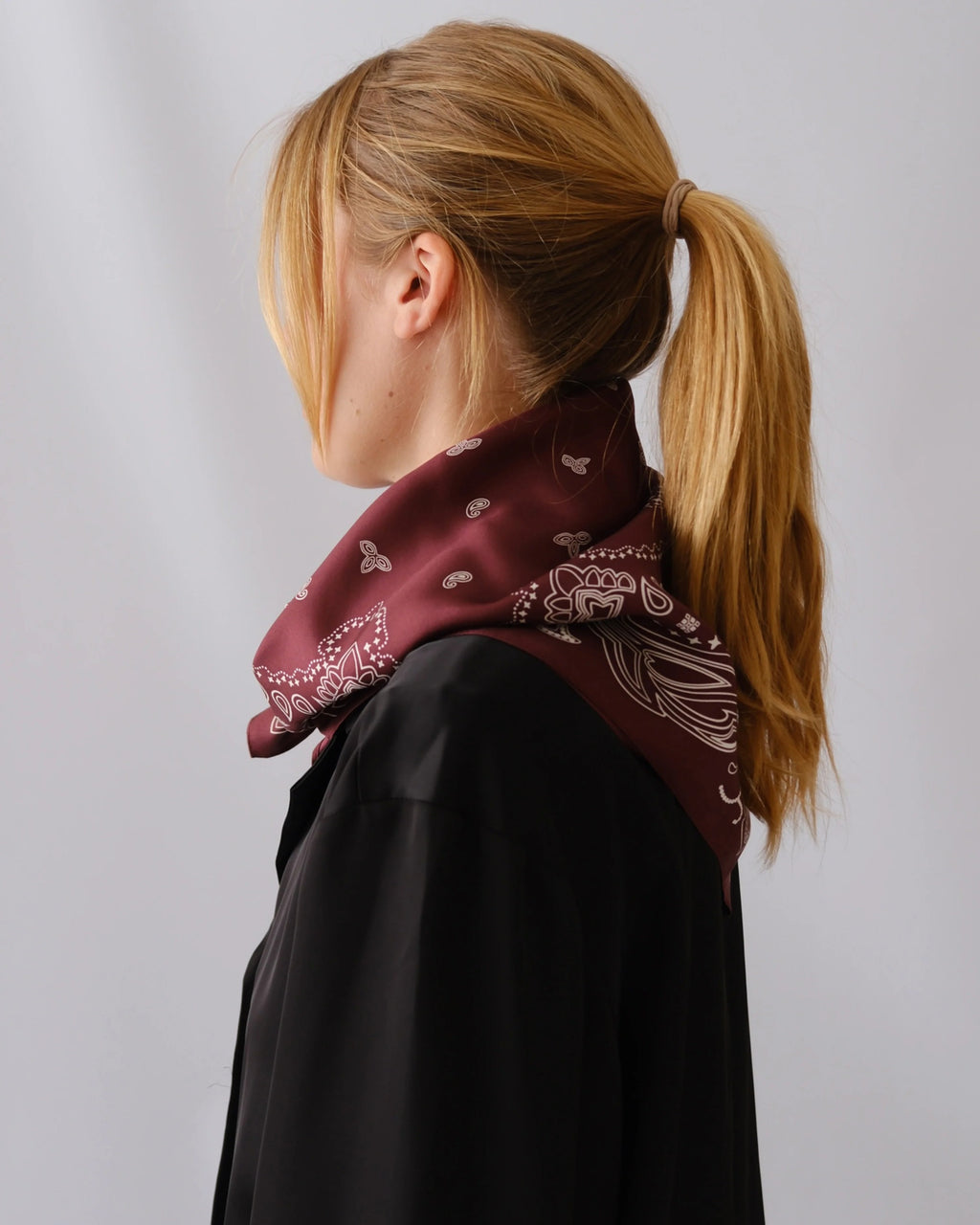 Lescarf Paisley Scarf in Wine Red worn at the neck with a ponytail, side profile