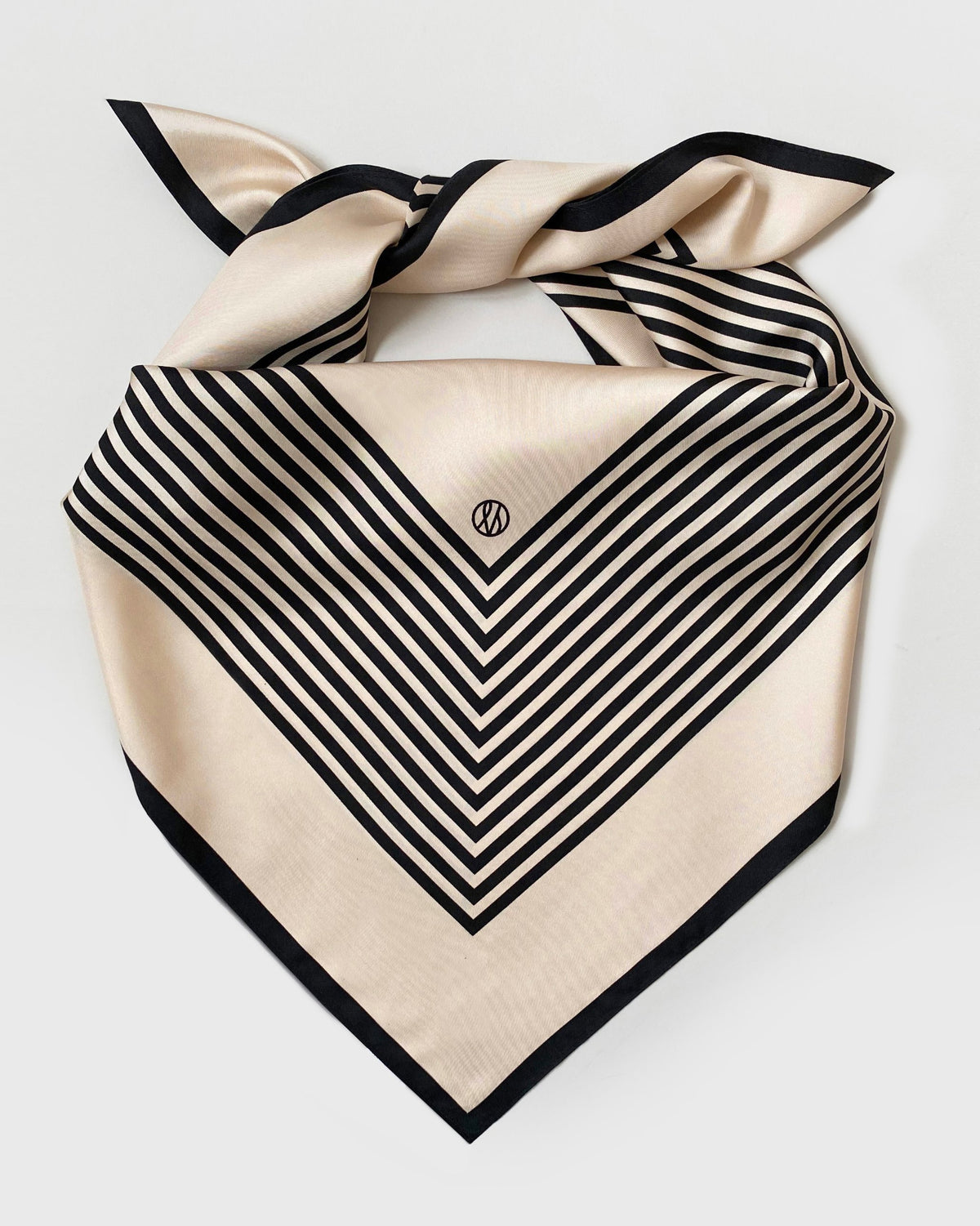 No.1 in Sand scarf by Lescarf folded and knotted, laid flat to show the black striped pattern on sand