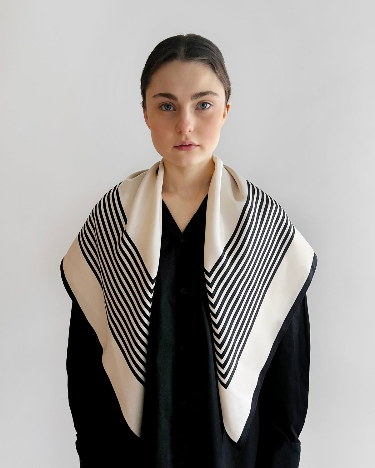 No.1 in Sand scarf by Lescarf worn around the neck with the striped points falling to the front over a black shirt