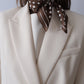 Polkadot Scarf in Brown by Lescarf knotted at the neck and worn with a cream blazer