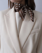 Polkadot Scarf in Brown by Lescarf knotted at the neck and worn with a cream blazer