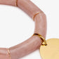 Close-up of the Flex Bracelet Blush Marble by Vanessa Baroni showing the tubular beads with gold discs and the gold logo disc