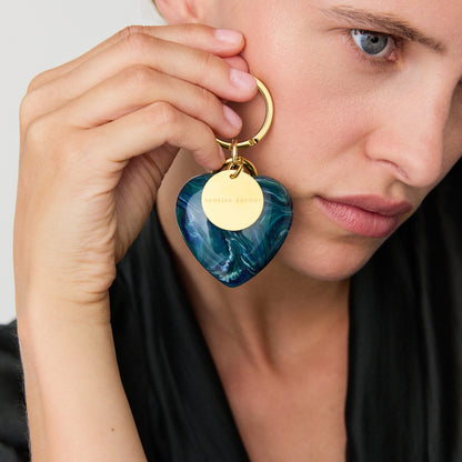 Heart Key Chain Charm In Teal Marble by Vanessa Baroni, held by a model