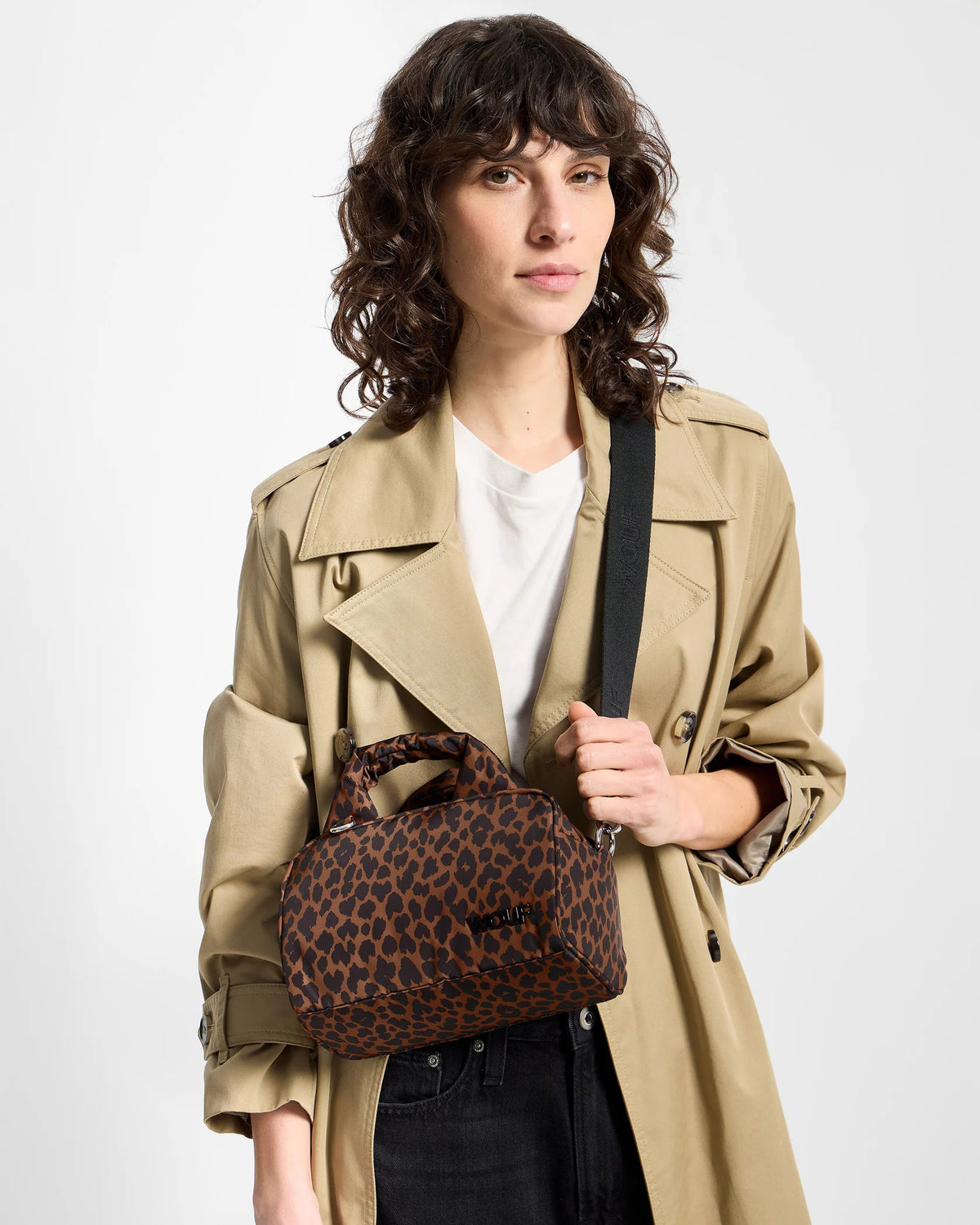Model wearing the WOUF Leo Bowling Bag across the body with a beige trench coat