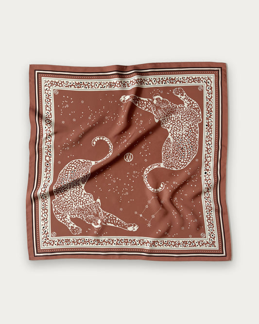 Zodiac Scarf Gemini in Terracotta by Lescarf, 65x65 cm, laid flat in terracotta with cream leopards, stars and a leopard-print border